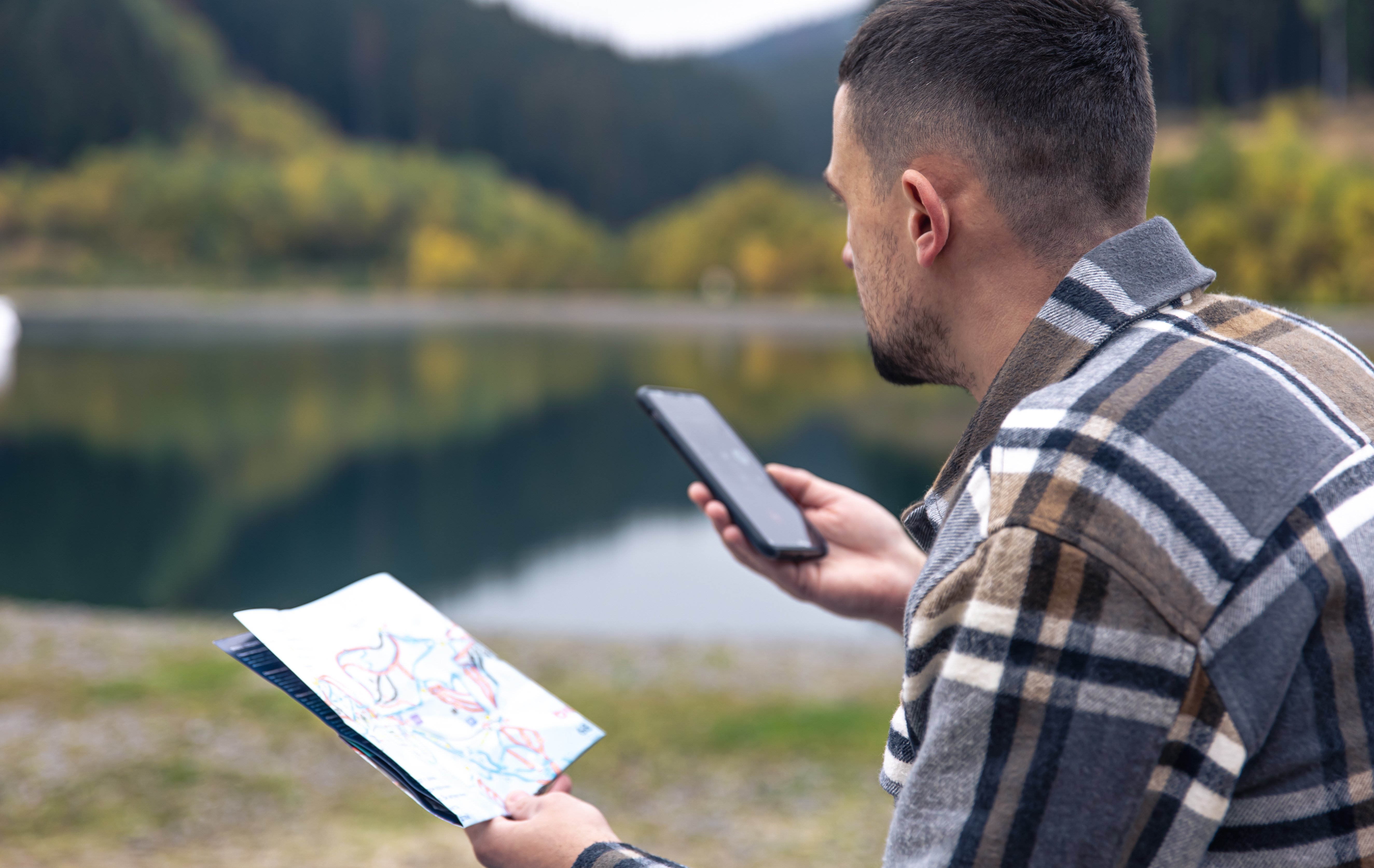 young-man-with-map-his-hands-against-backdrop-mountains